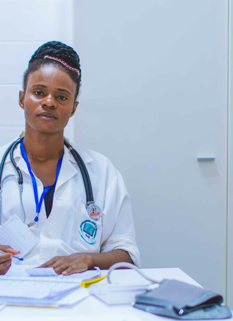 A woman receiving a breast cancer diagnosis. She is sitting in a doctor's office, listening attentively and taking notes.