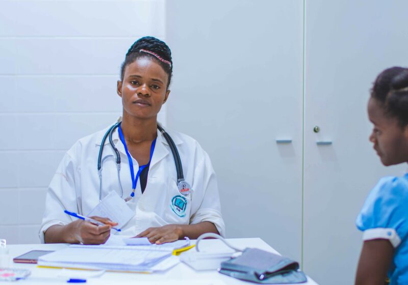 A woman receiving a breast cancer diagnosis. She is sitting in a doctor's office, listening attentively and taking notes.